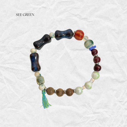 Handcrafted beaded bracelet featuring colorful ceramic beads, silver fish charm, and natural accents, inspired by ocean breezes and bohemian style.